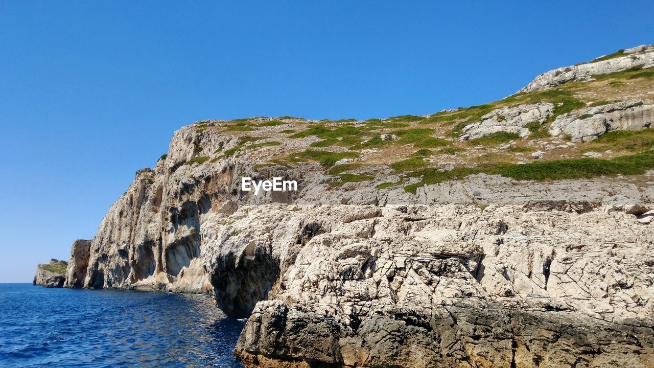 SCENIC VIEW OF ROCK FORMATION IN SEA AGAINST CLEAR BLUE SKY