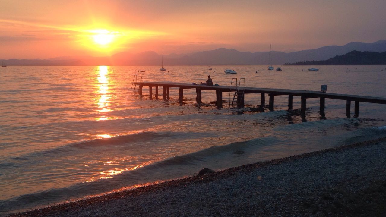 Pier over sea against sky during sunset