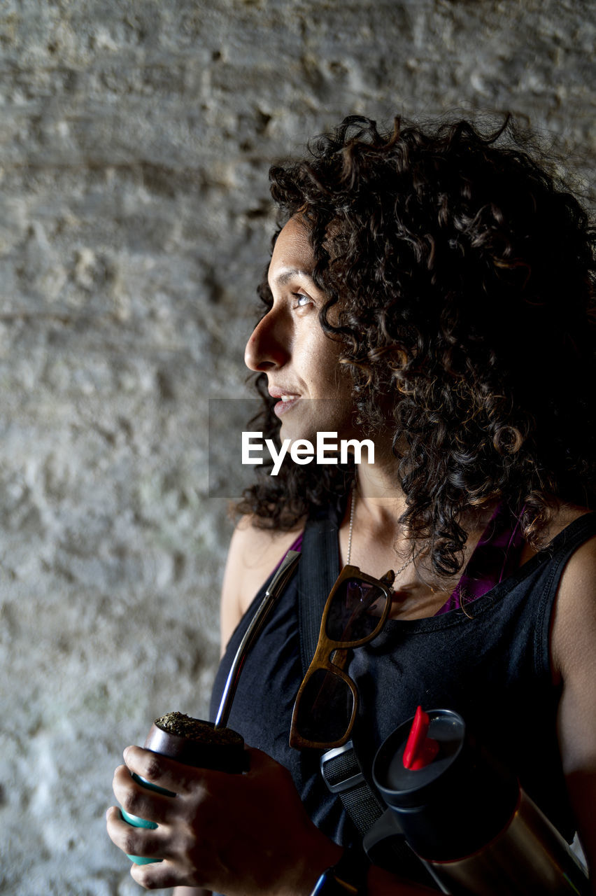 Profile view of a mixed race woman drinking mate.