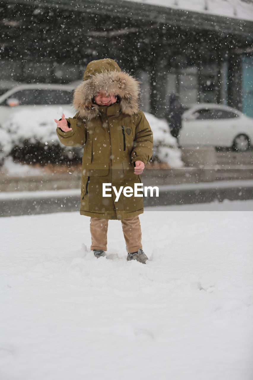 Happy boy enjoying snowfall in city