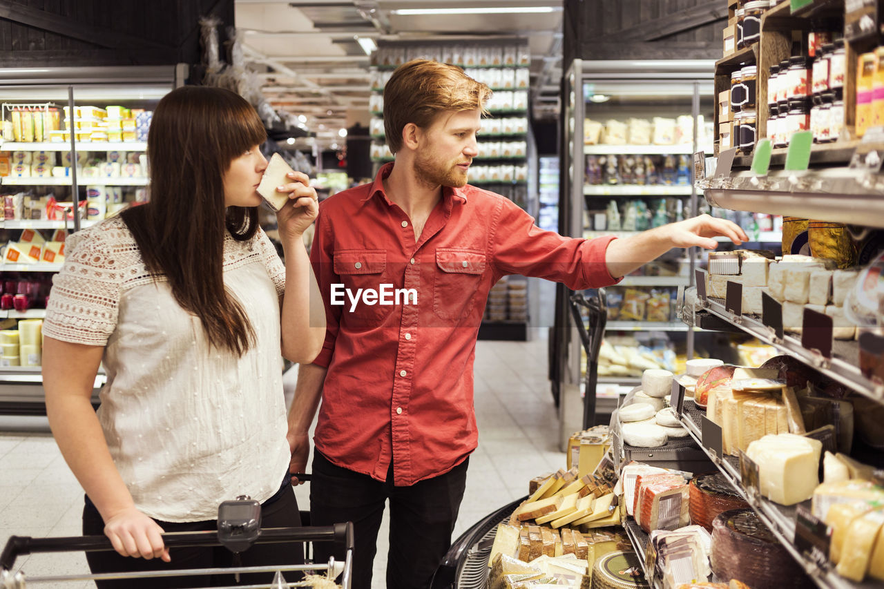 Young couple shopping cheese at supermarket