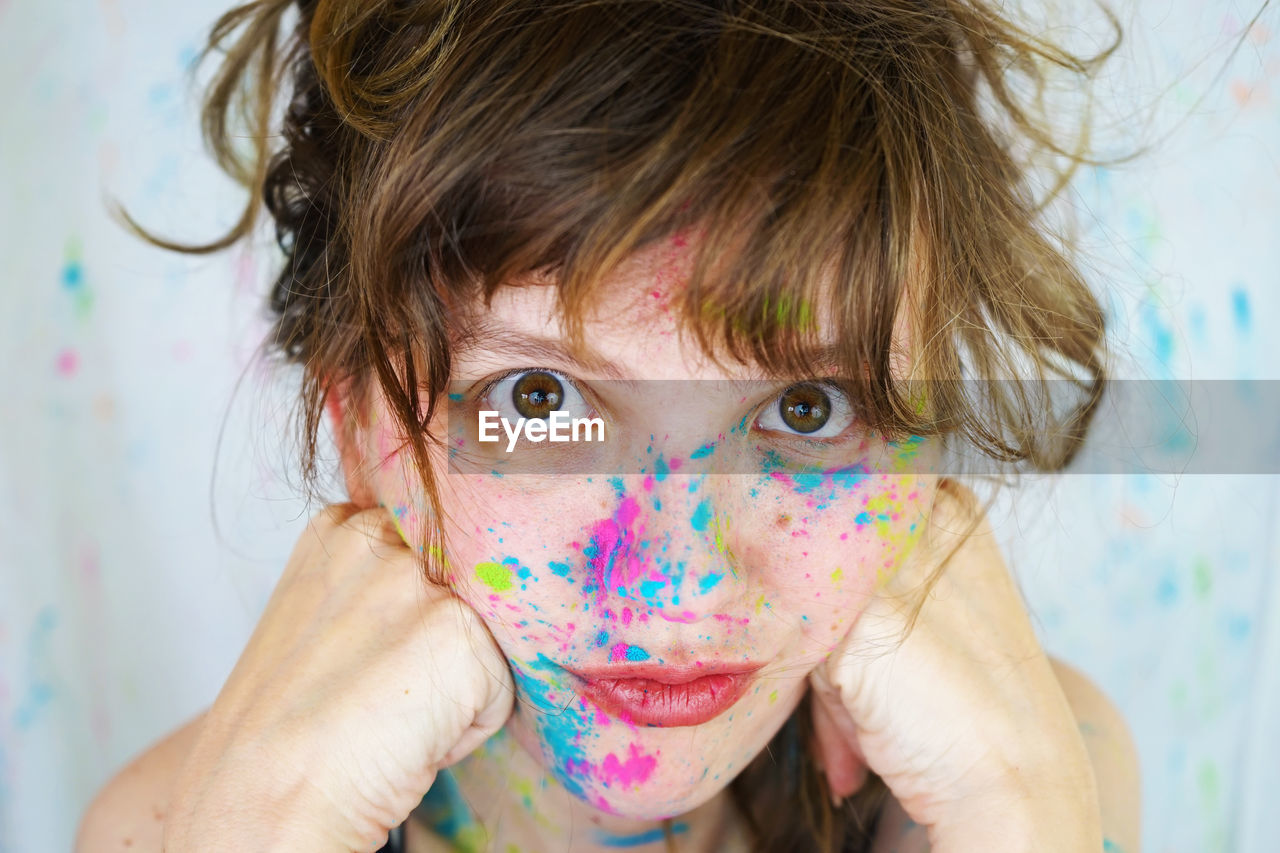 Close-up portrait of young woman covered in powder paint with brown hair