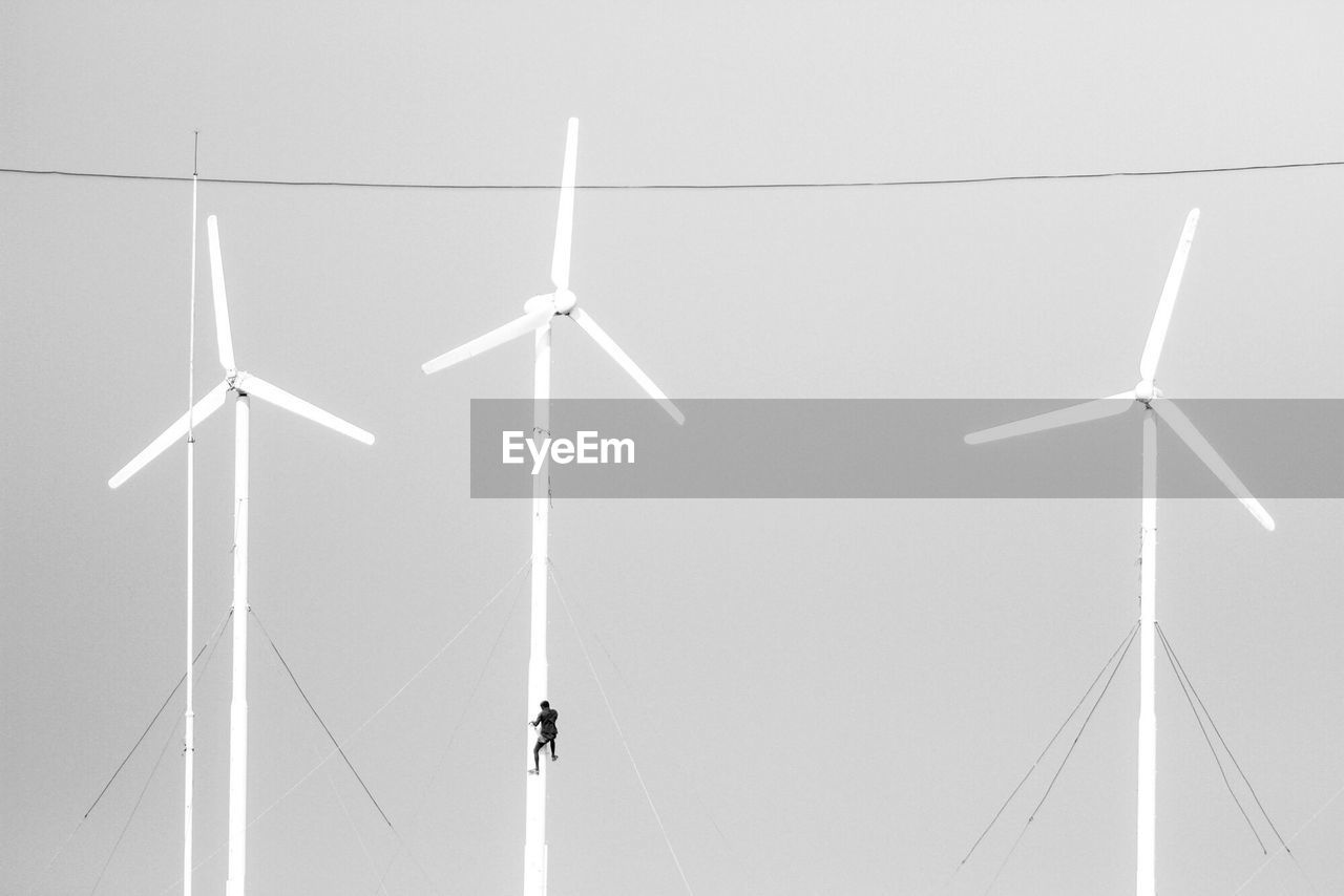 Low angle view of person climbing on wind turbine