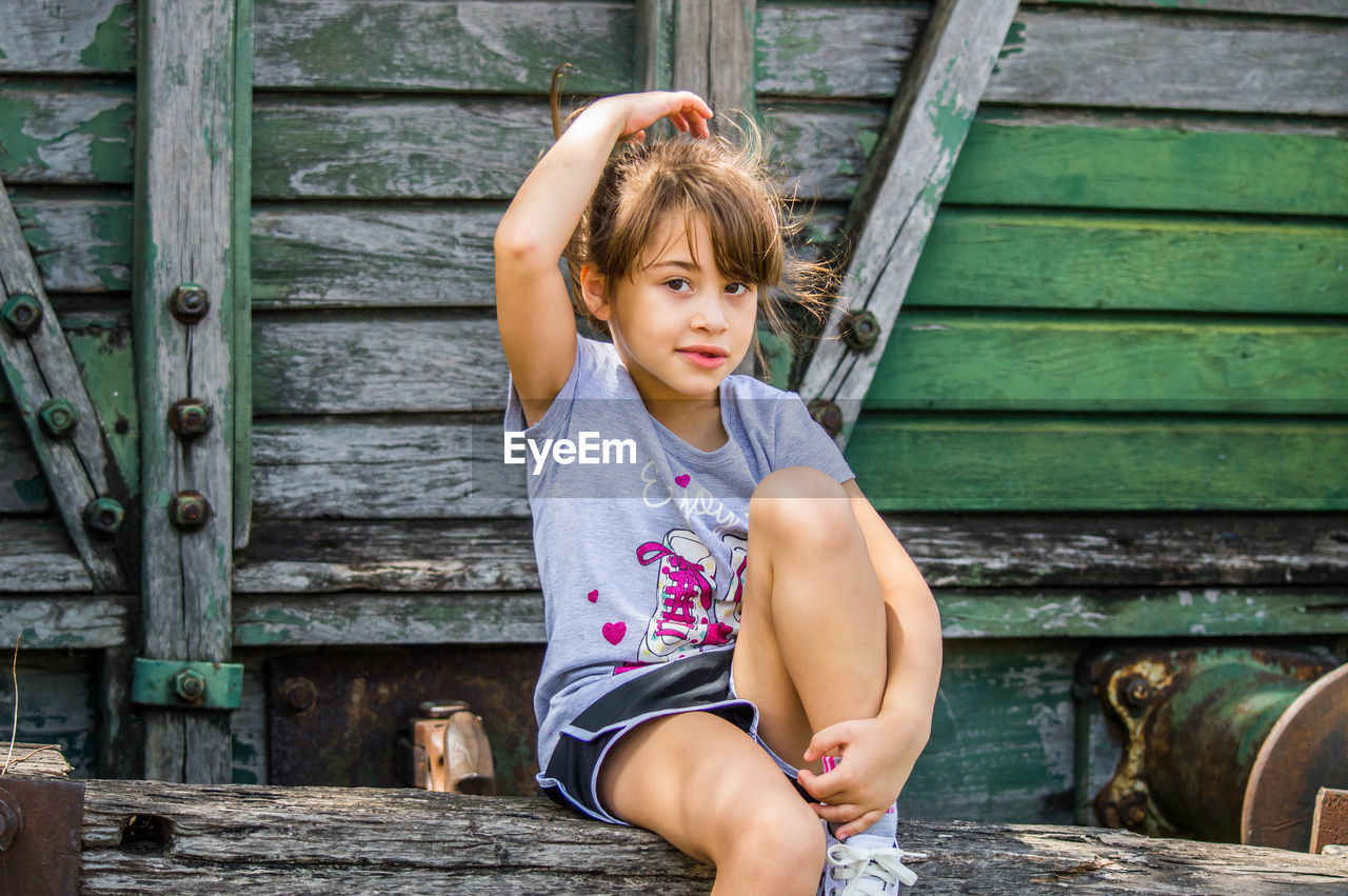 Little blonde girl posing in front of old train wagon