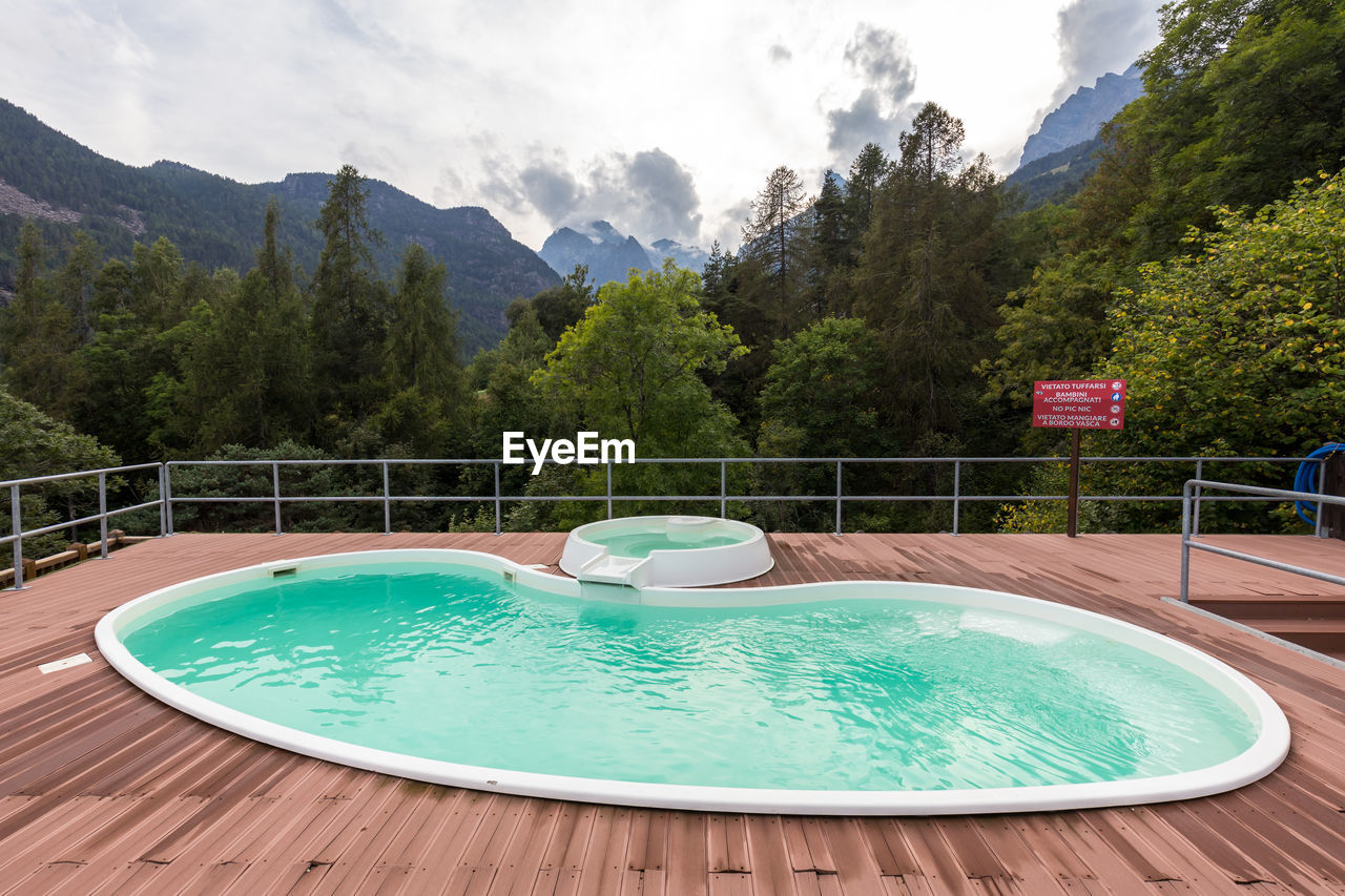 SWIMMING POOL BY TREE AGAINST SKY