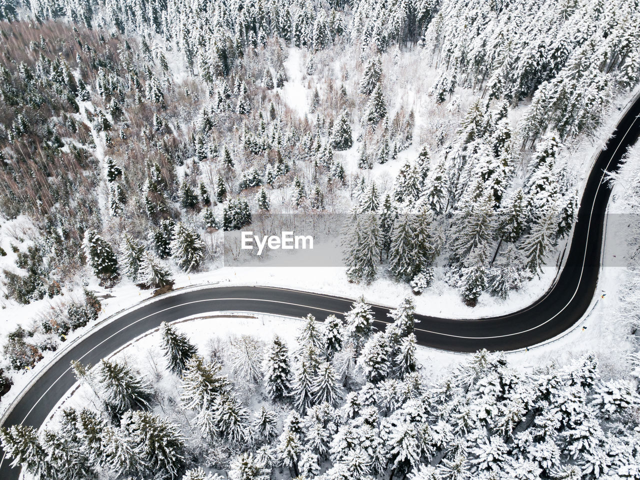 Aerial view of a road winding through snow covered forest