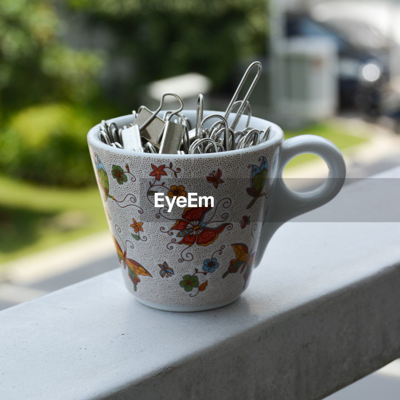 Portrait of a tiny cup filled with metal binder clips on a white surface 