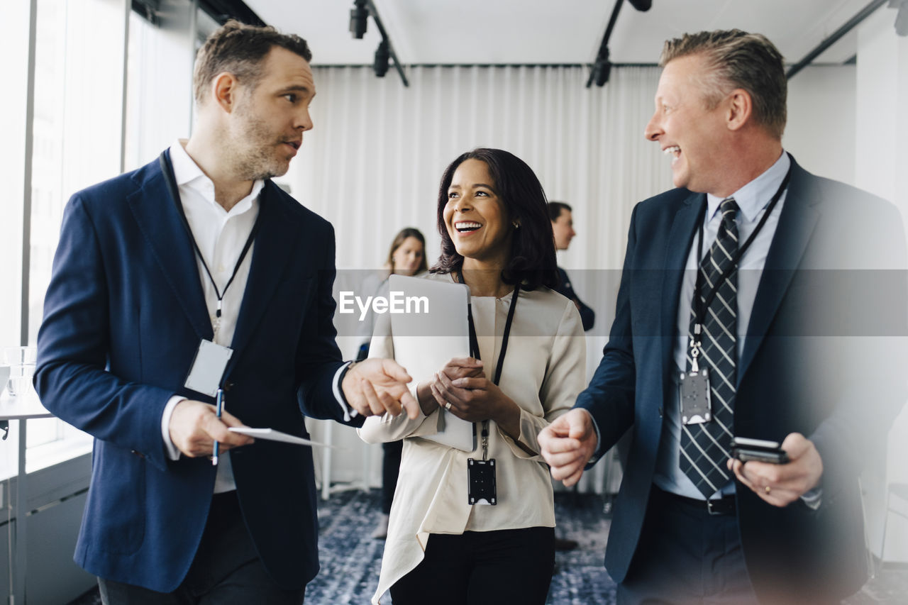 Happy entrepreneurs talking to male coworker in office