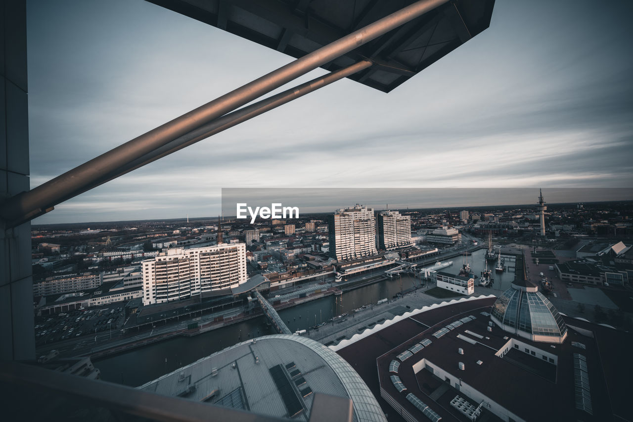 HIGH ANGLE VIEW OF ROAD BY BUILDINGS AGAINST SKY