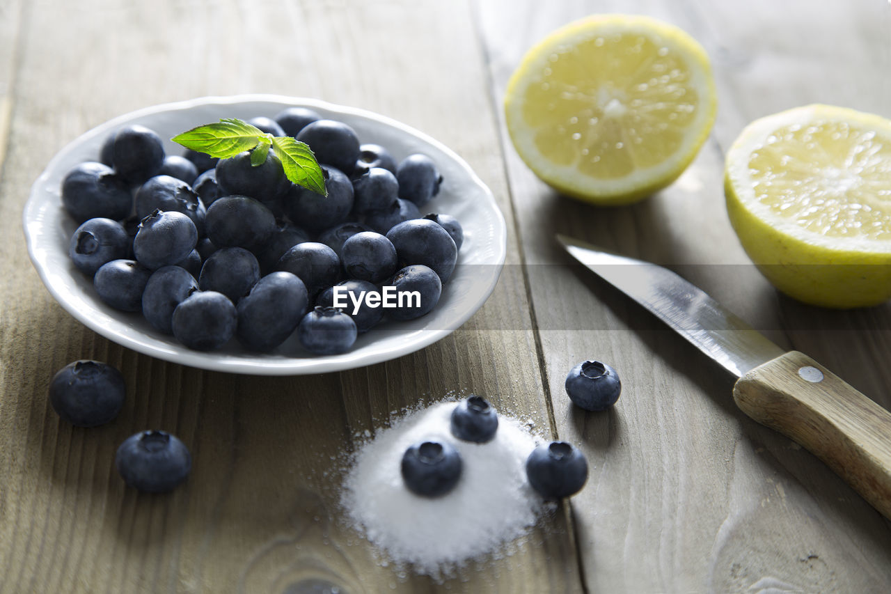 Close-up of blueberries with sliced lemon and salt on wooden table