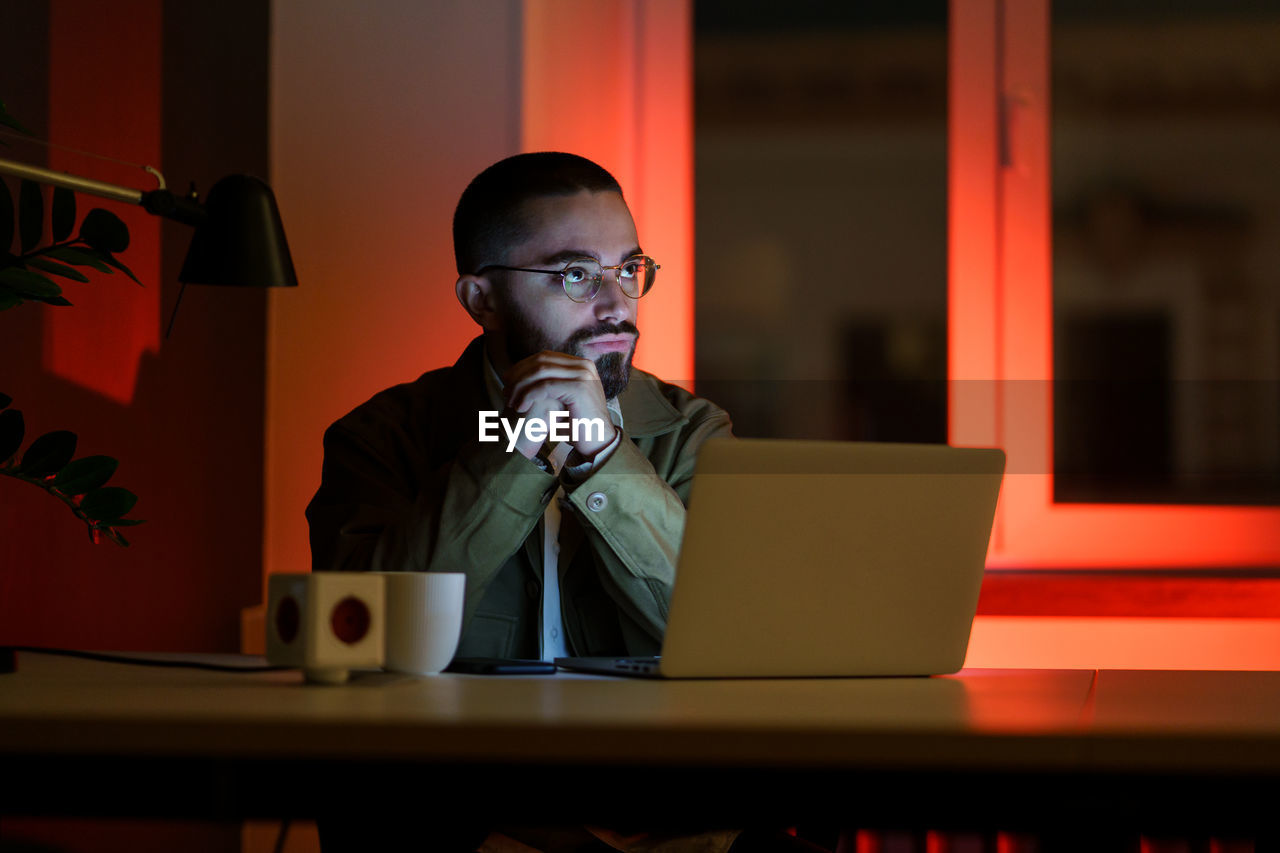 Pensive manager, web designer work late in empty closed coworking space. overwork time and overtime