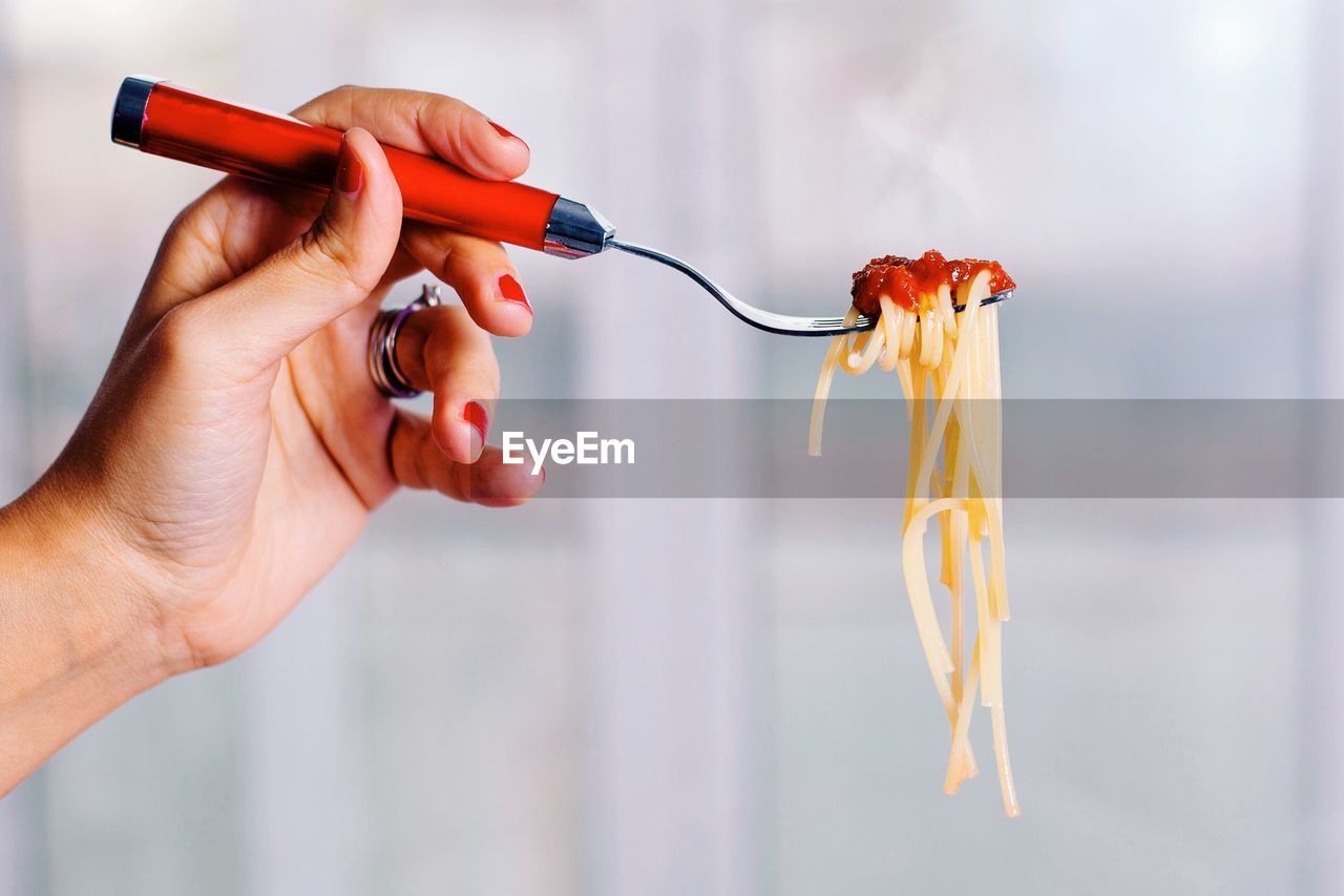Cropped hand holding fork with pasta