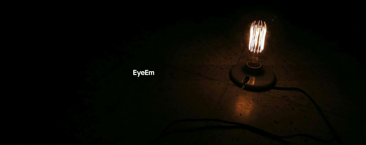 High angle view of illuminated light bulb on floor at night