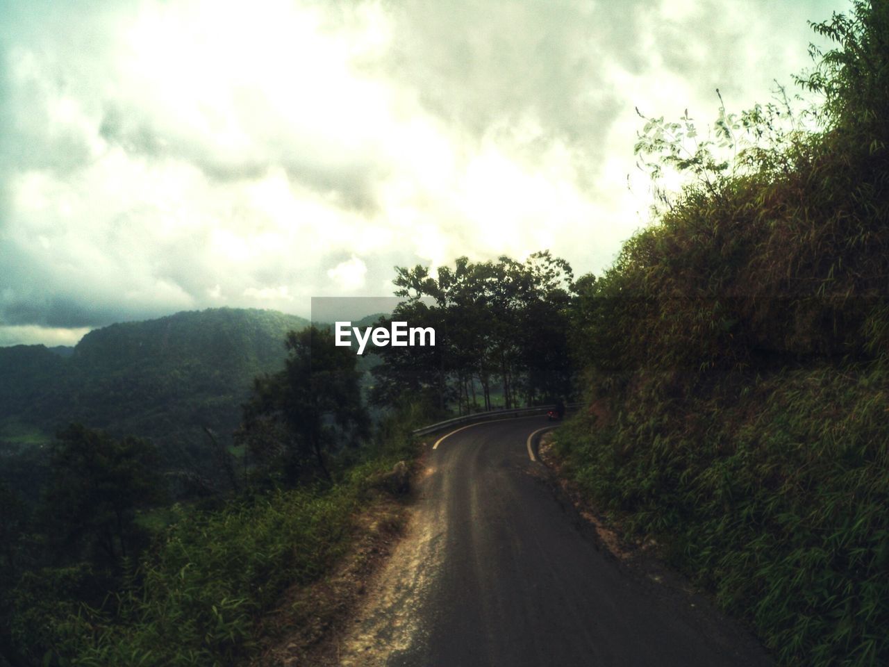 Mountain road against cloudy sky