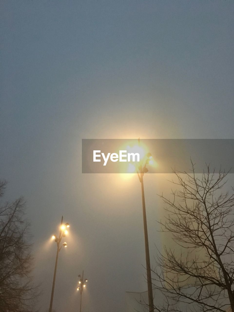 LOW ANGLE VIEW OF ILLUMINATED STREET LIGHT AT SUNSET