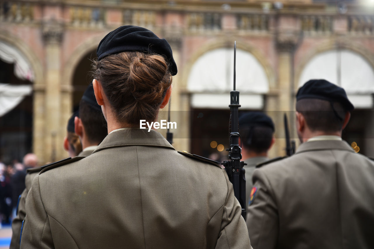 Rear view of female police with rifle in city