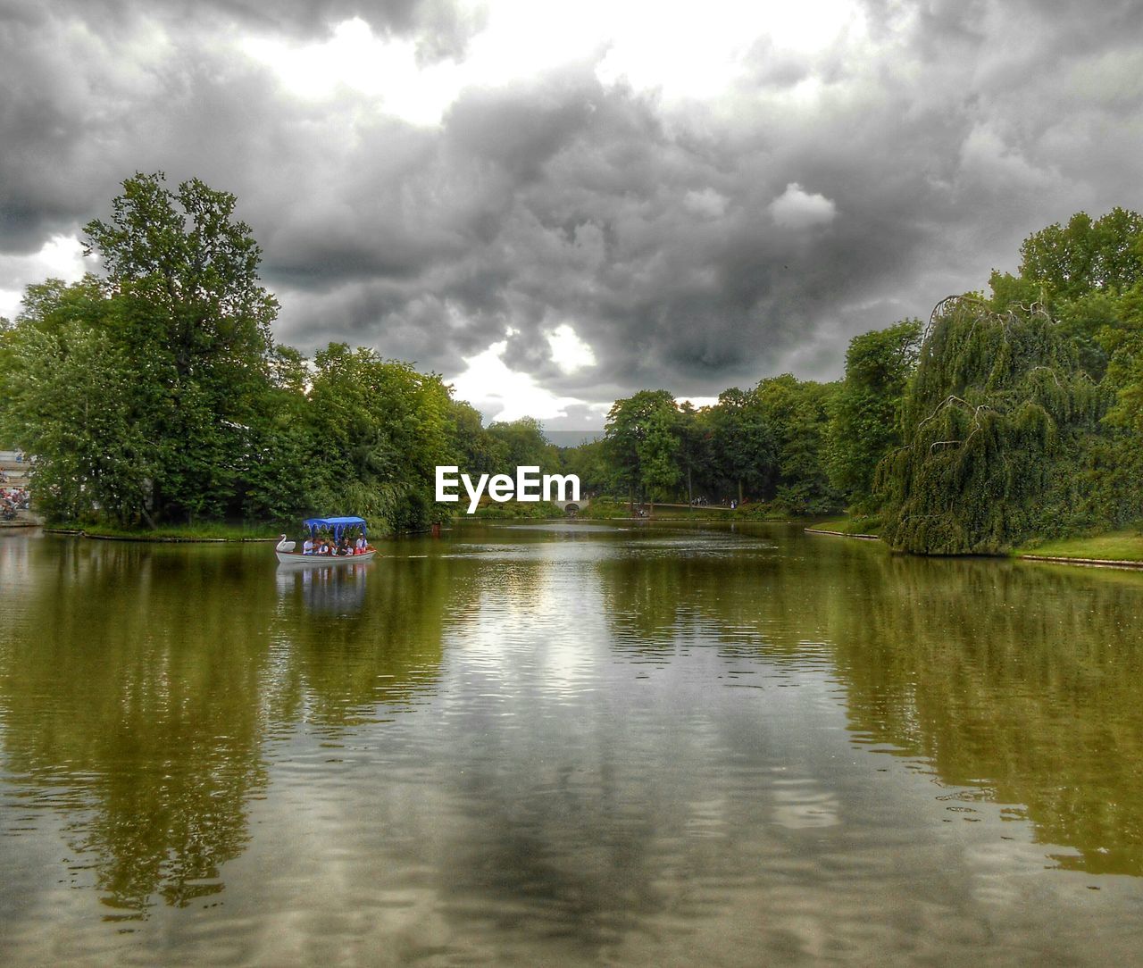 Scenic view of river by trees against cloudy sky