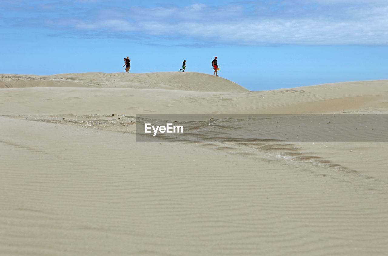 People at desert against sky