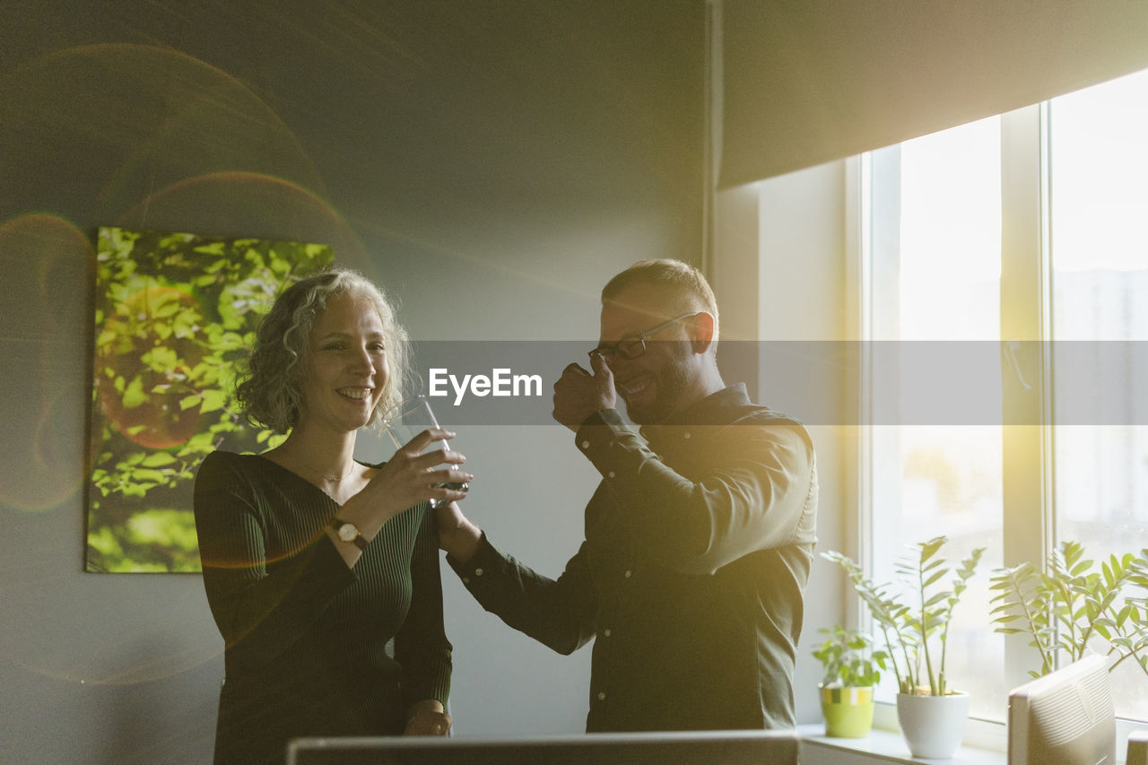 Happy businessman and businesswoman in office in backlight