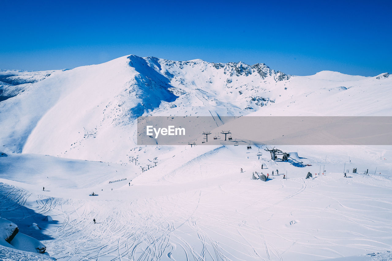 Aerial view of snow covered landscape against blue sky