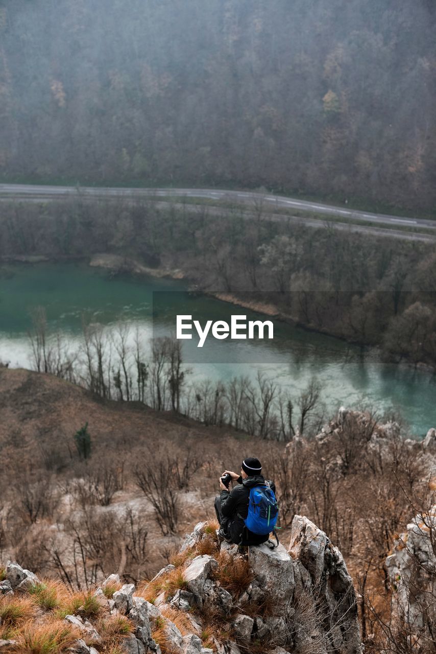 Man sitting by river on rock