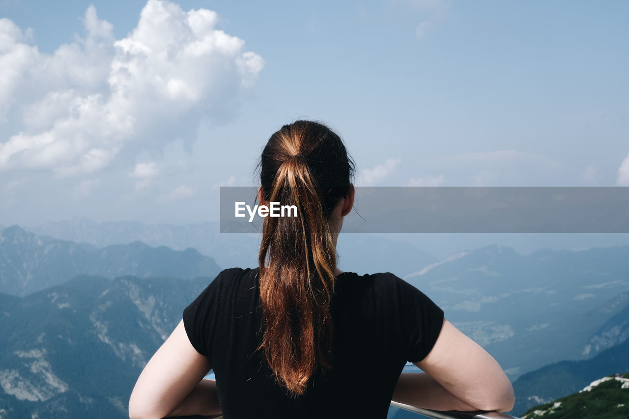 Rear view of woman standing against mountains and sky