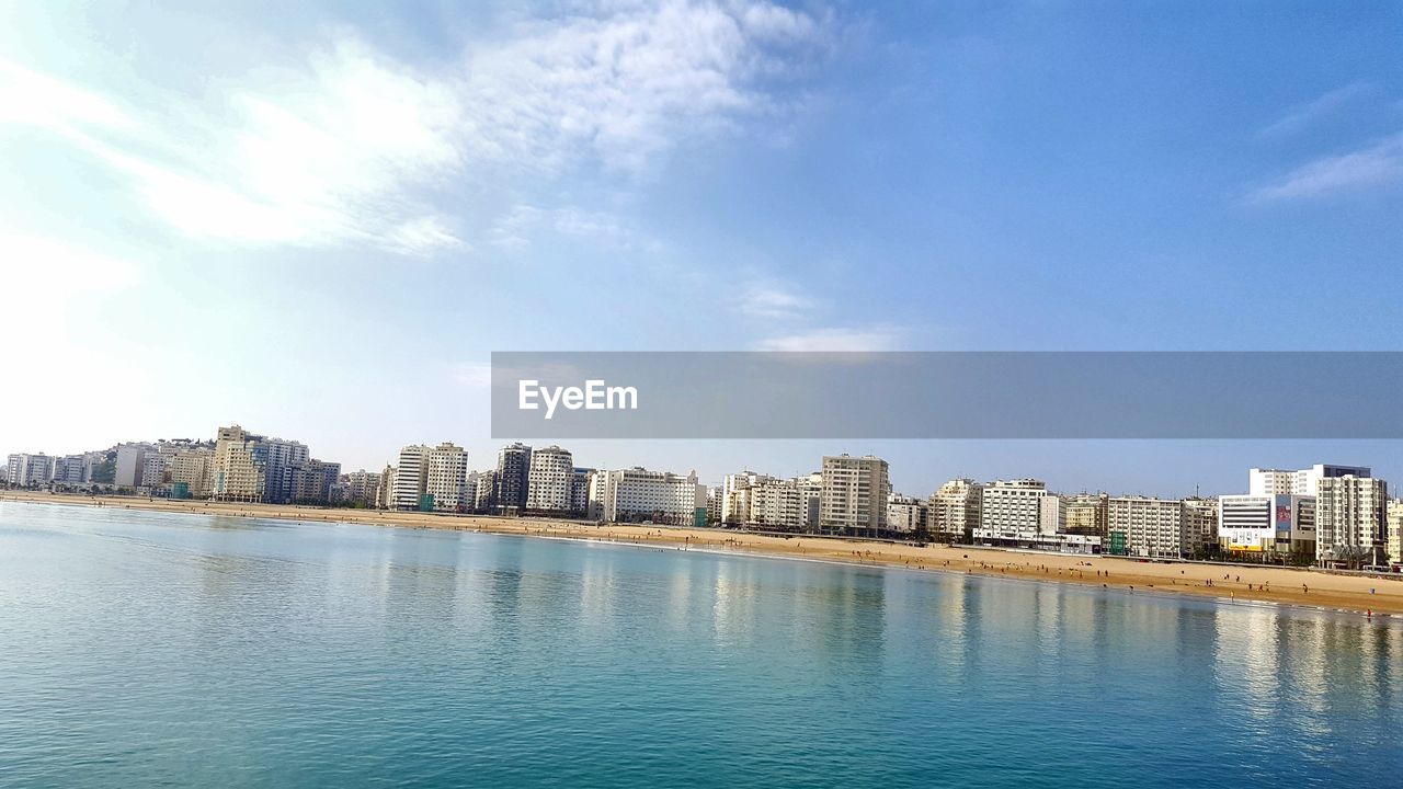 SEA BY BUILDINGS AGAINST SKY IN CITY