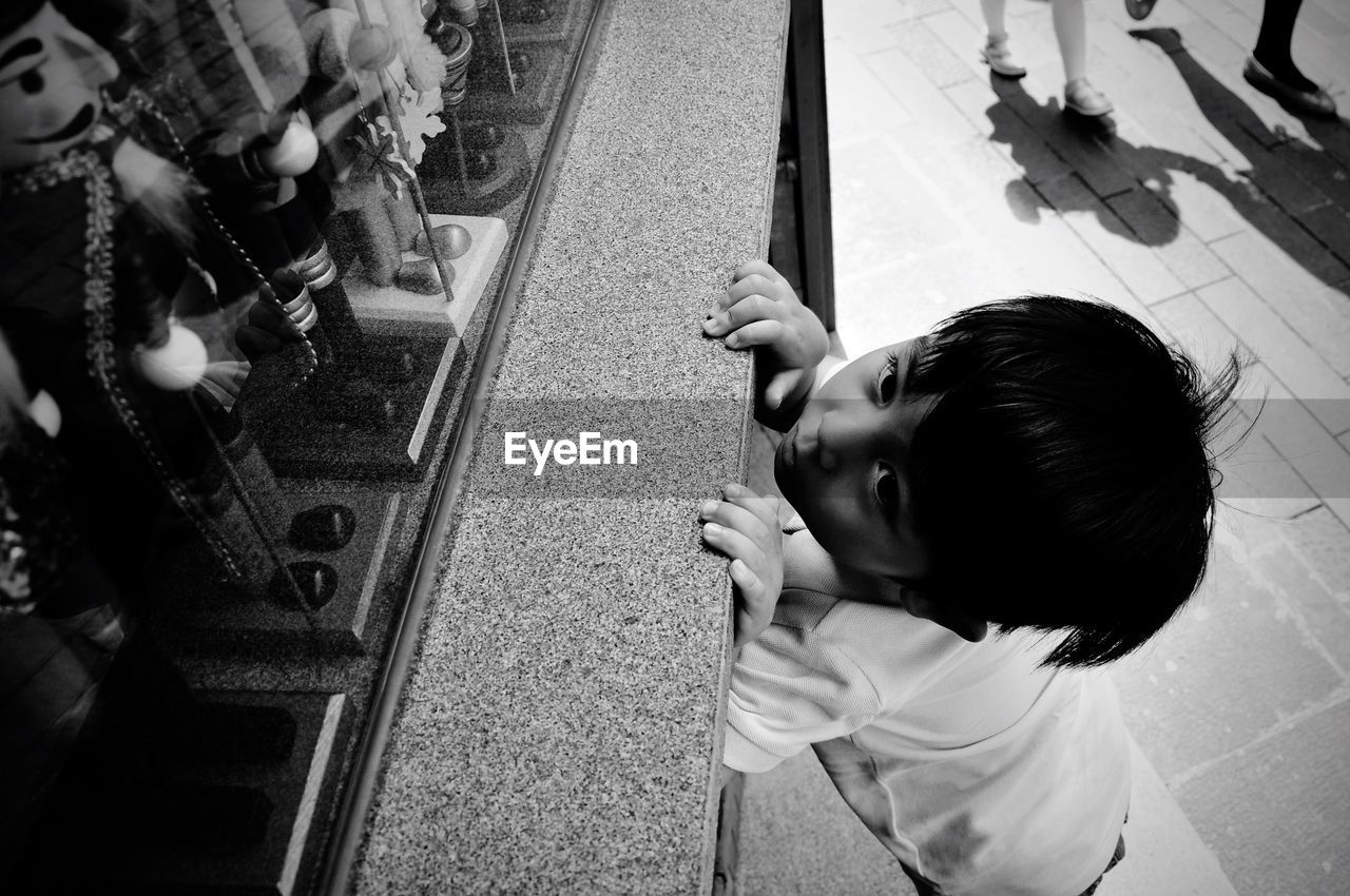 High angle view of boy looking at toys in display cabinet