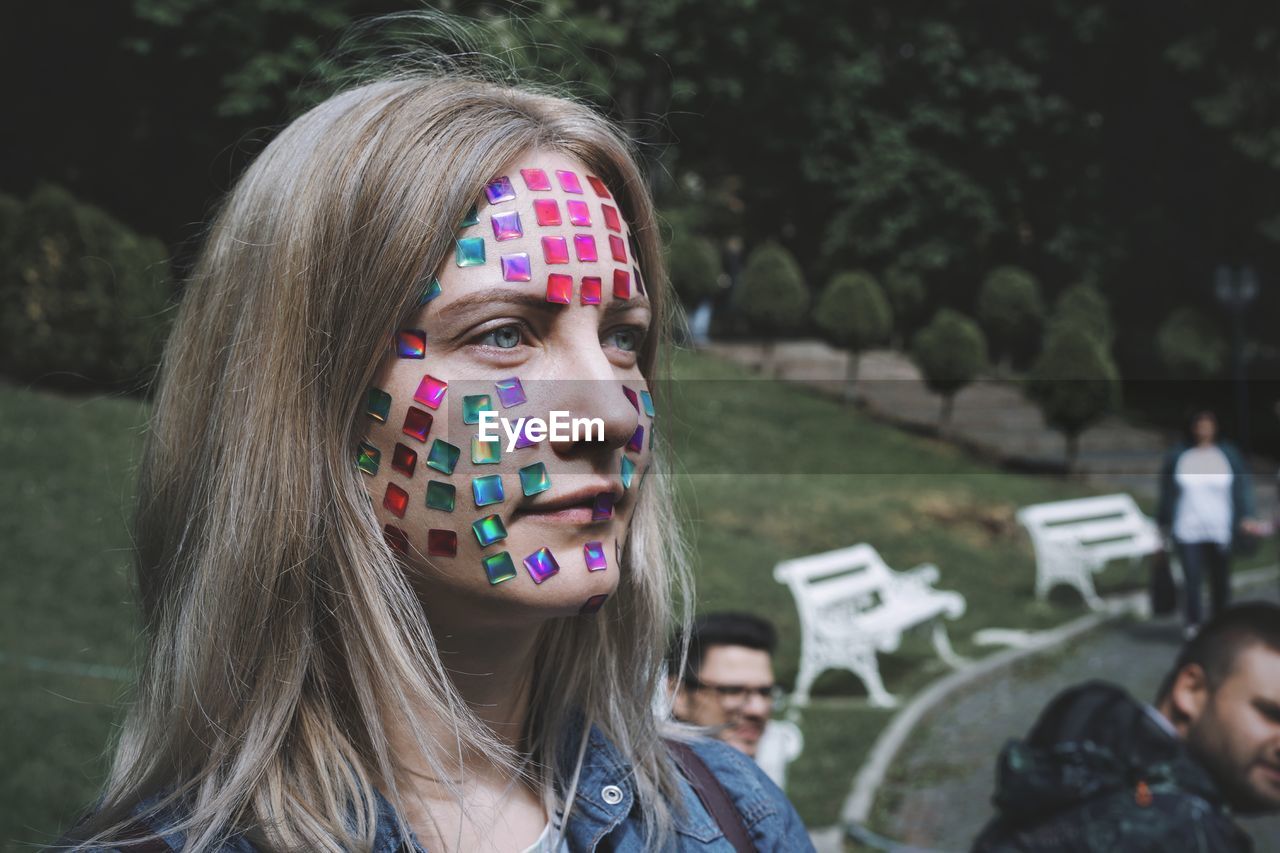 Close-up of mid adult woman with colorful stickers on face