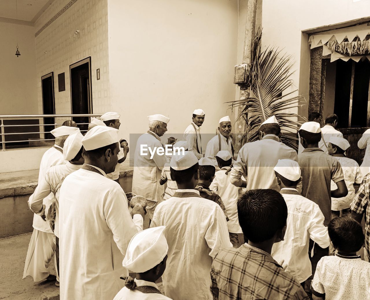 REAR VIEW OF PEOPLE STANDING AGAINST BUILDING