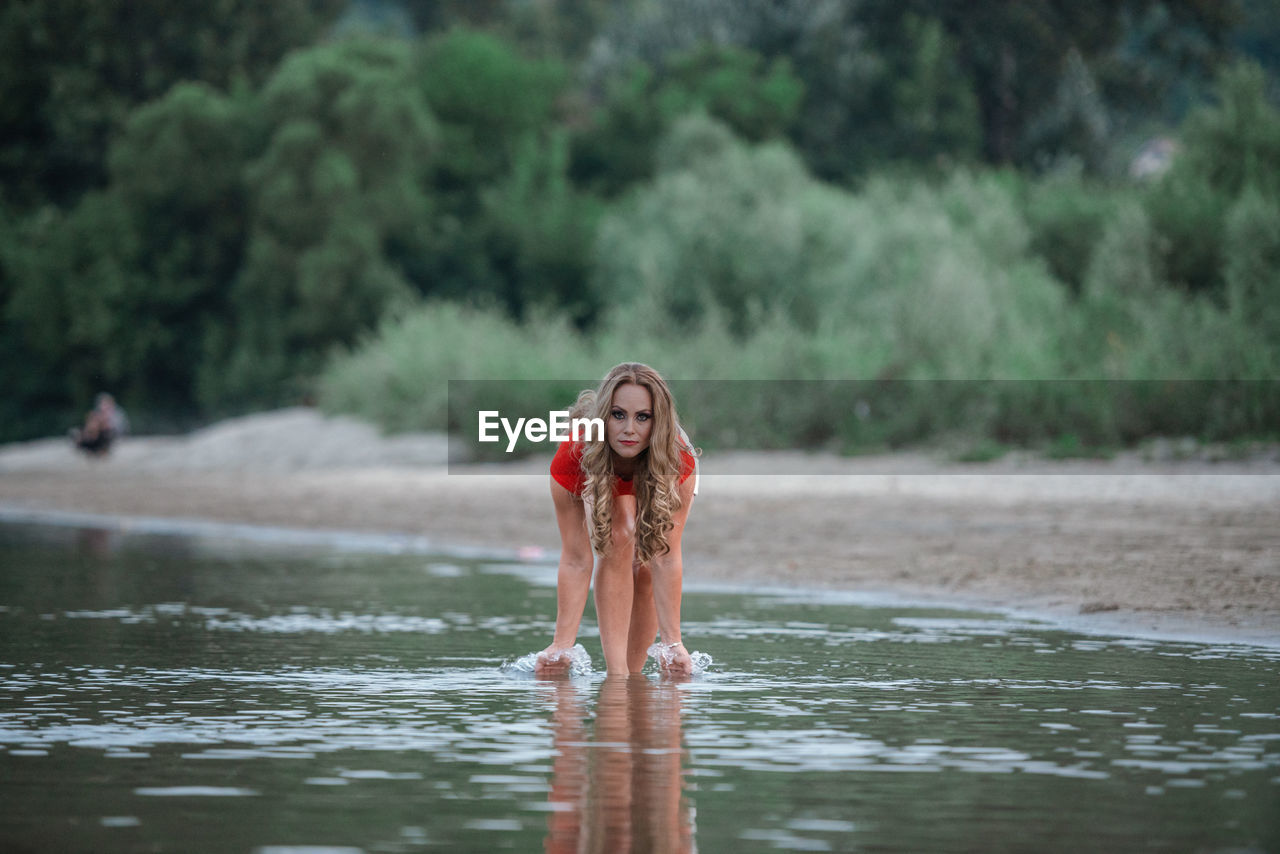 Woman standing by tree against waterfall