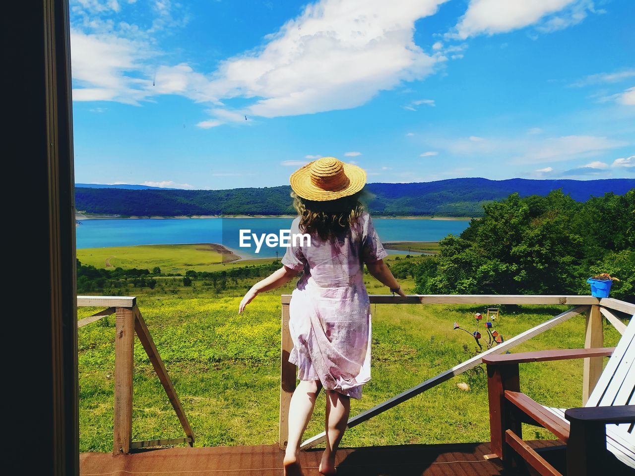 REAR VIEW OF WOMAN LOOKING AT VIEW OF RAILING AGAINST SKY