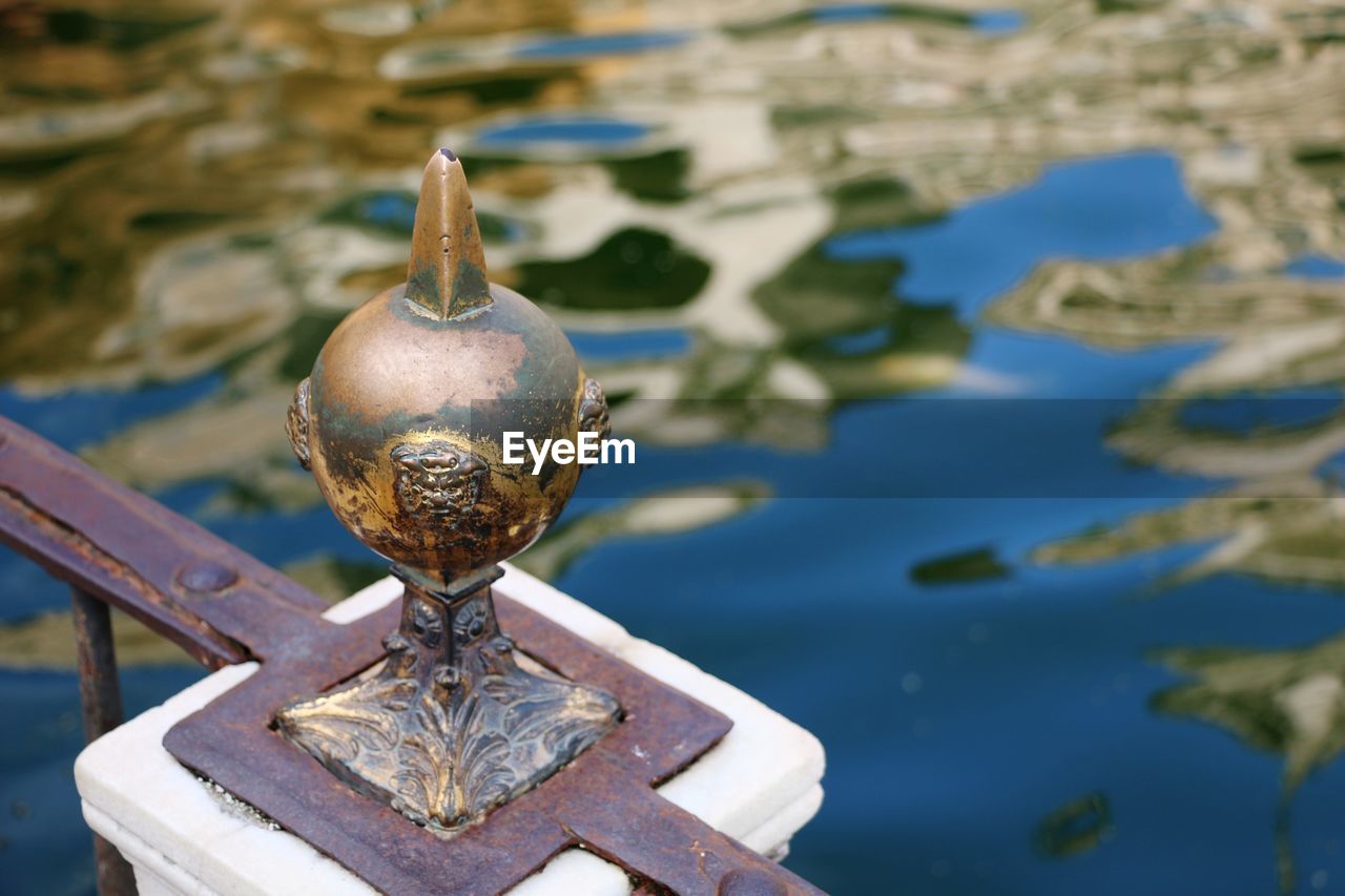 Close-up of metallic railing by pond