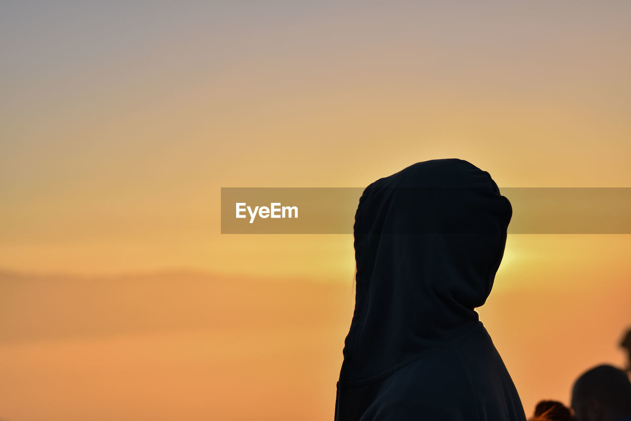 Woman wearing headscarf against sky during sunset