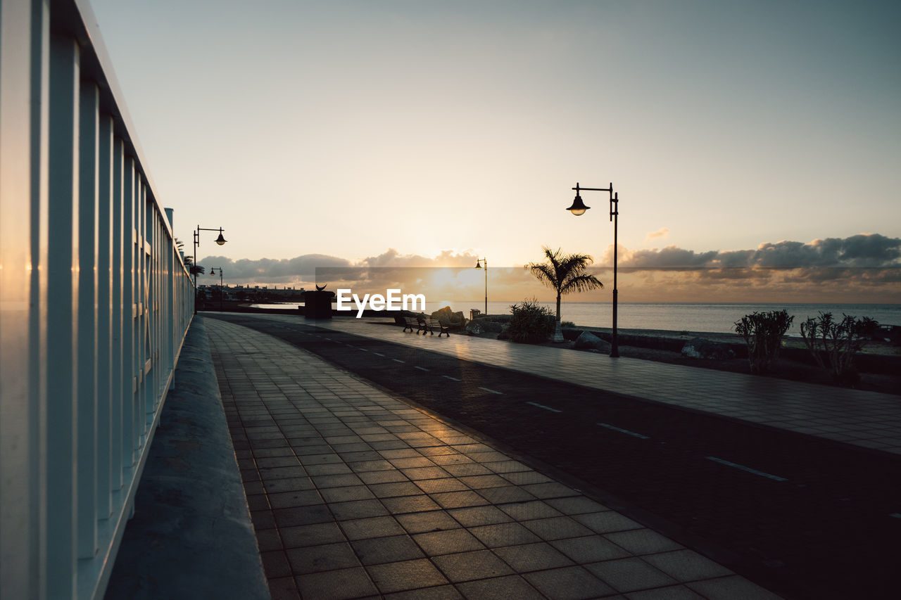 Promenade by sea against sky during sunset