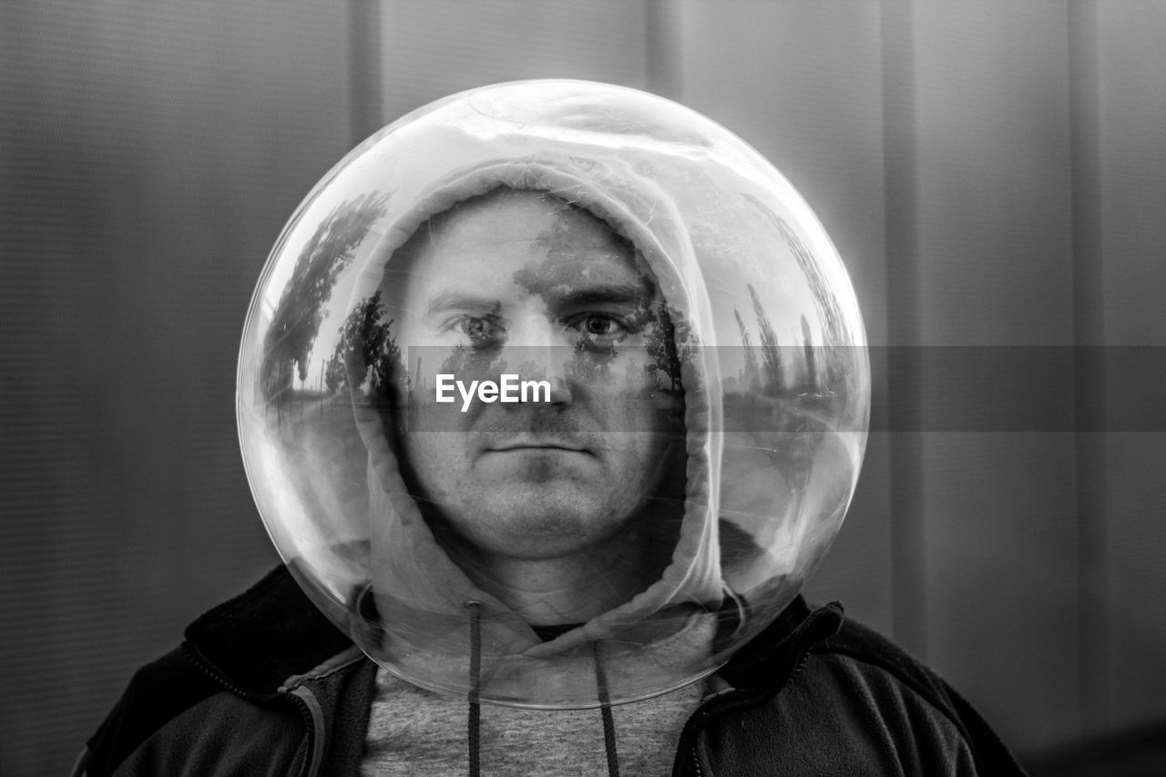 Portrait of man wearing spherical shape glass against wall