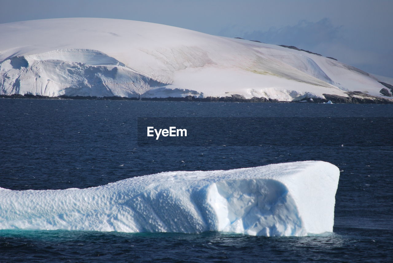 Scenic view of sea and snowcapped mountain against sky