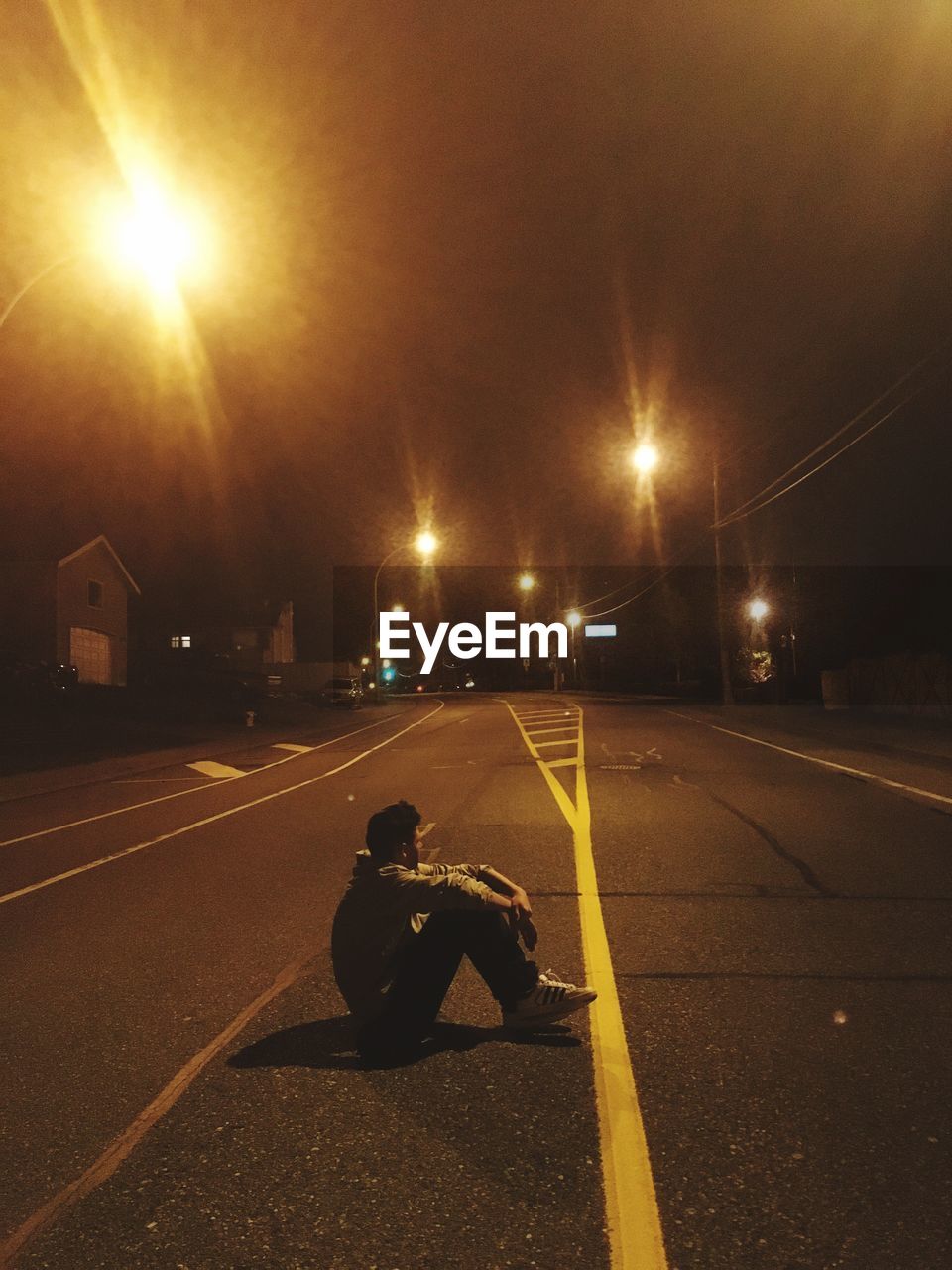 Man sitting on road at night