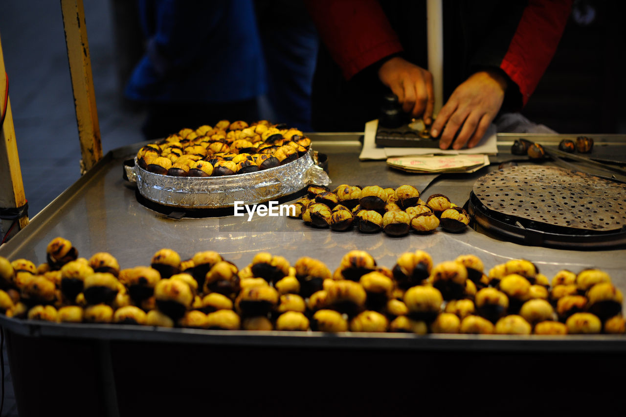 Midsection of vendor preparing food at market stall