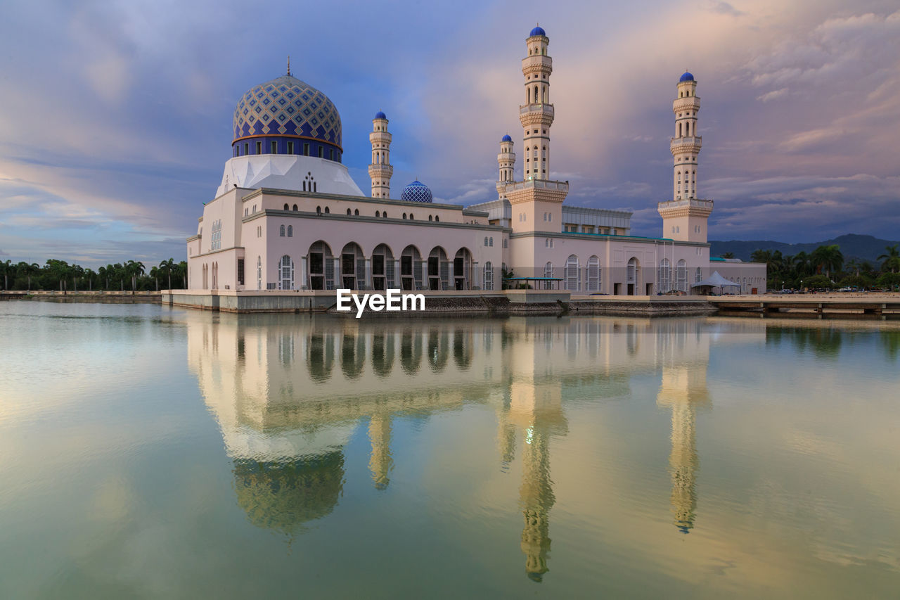 Mosque by lake against sky