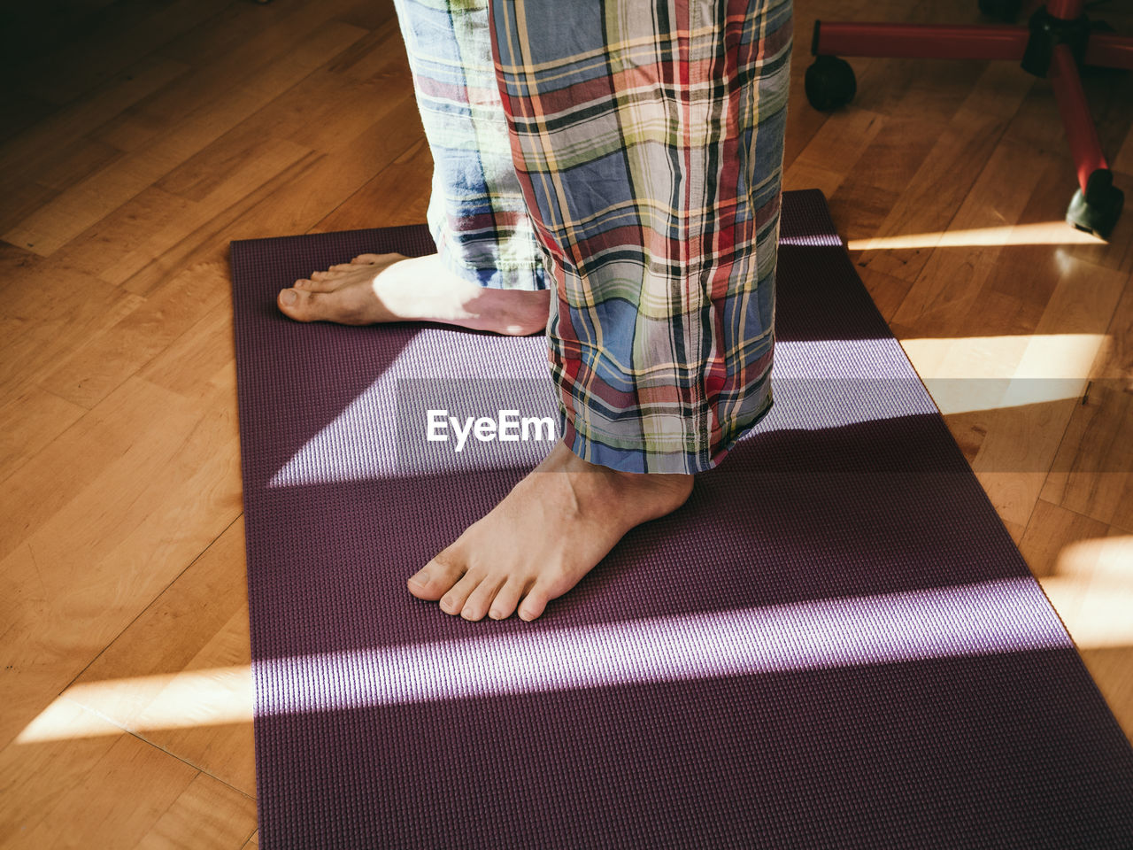 Low section of a man wearing pijamas standing on a yoga mat at home