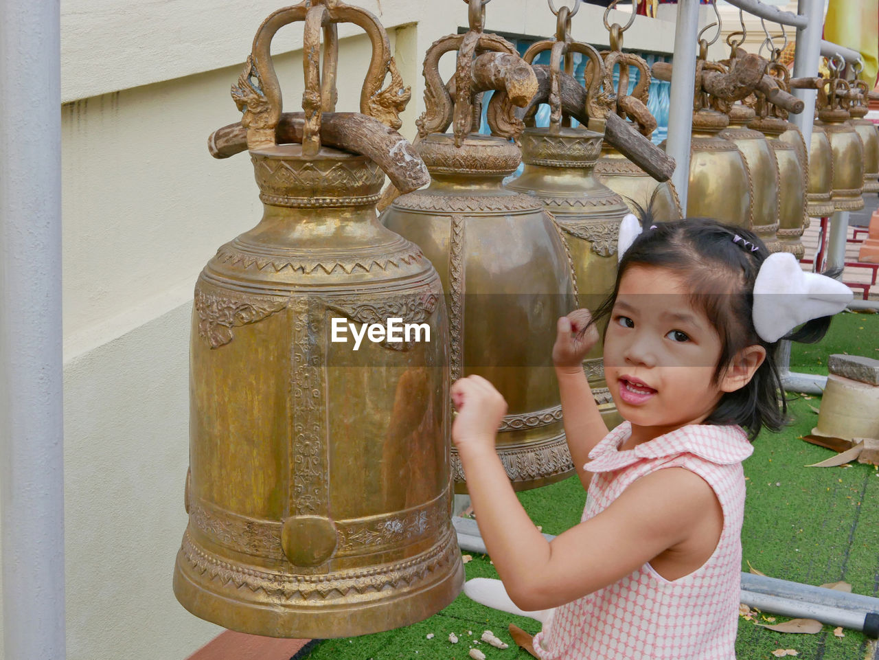 Close-up portrait of girl ringing bell at temple