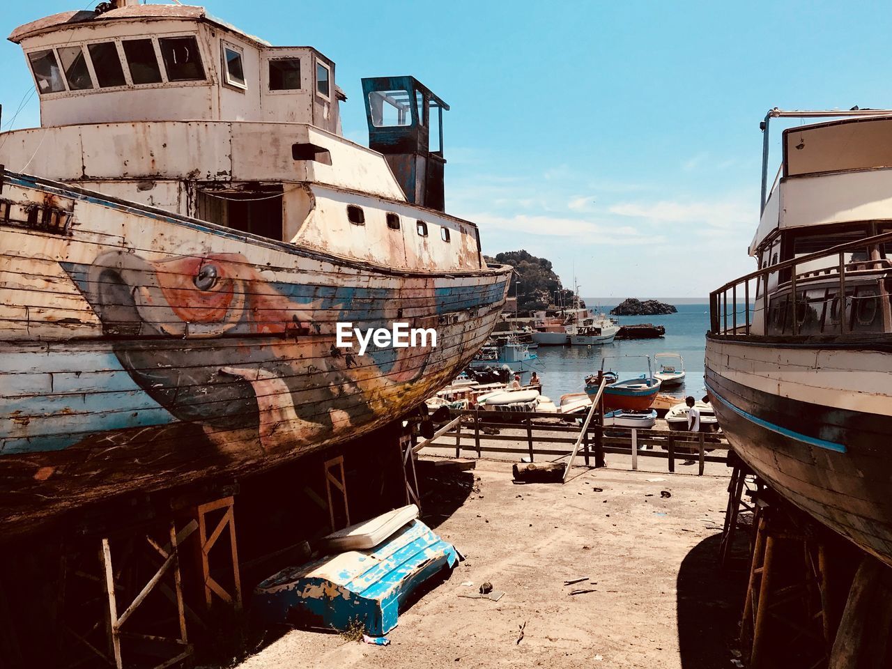 ABANDONED BOATS MOORED ON BEACH AGAINST SKY