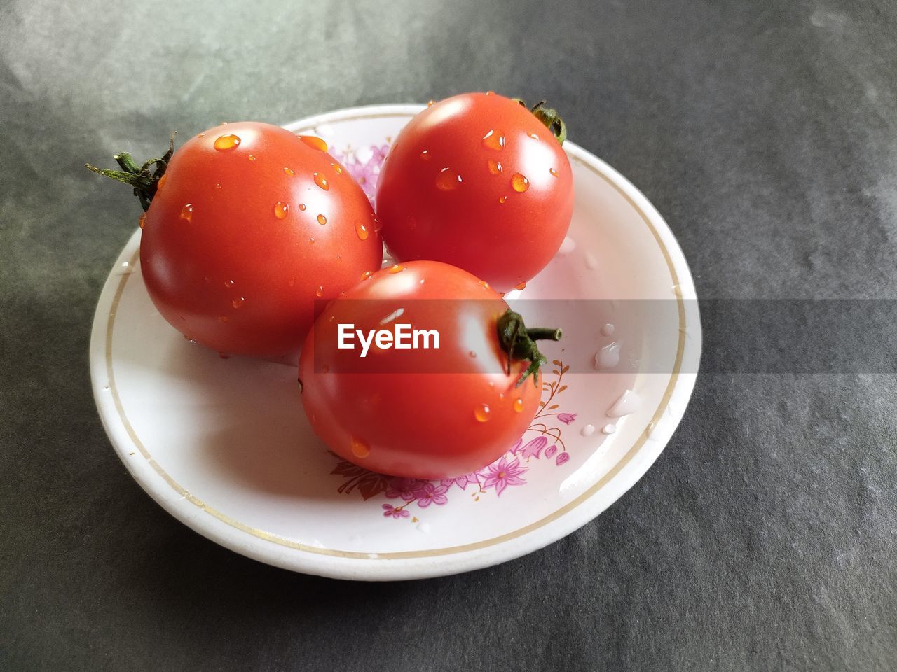 Indian tomatoes on plate, black background.