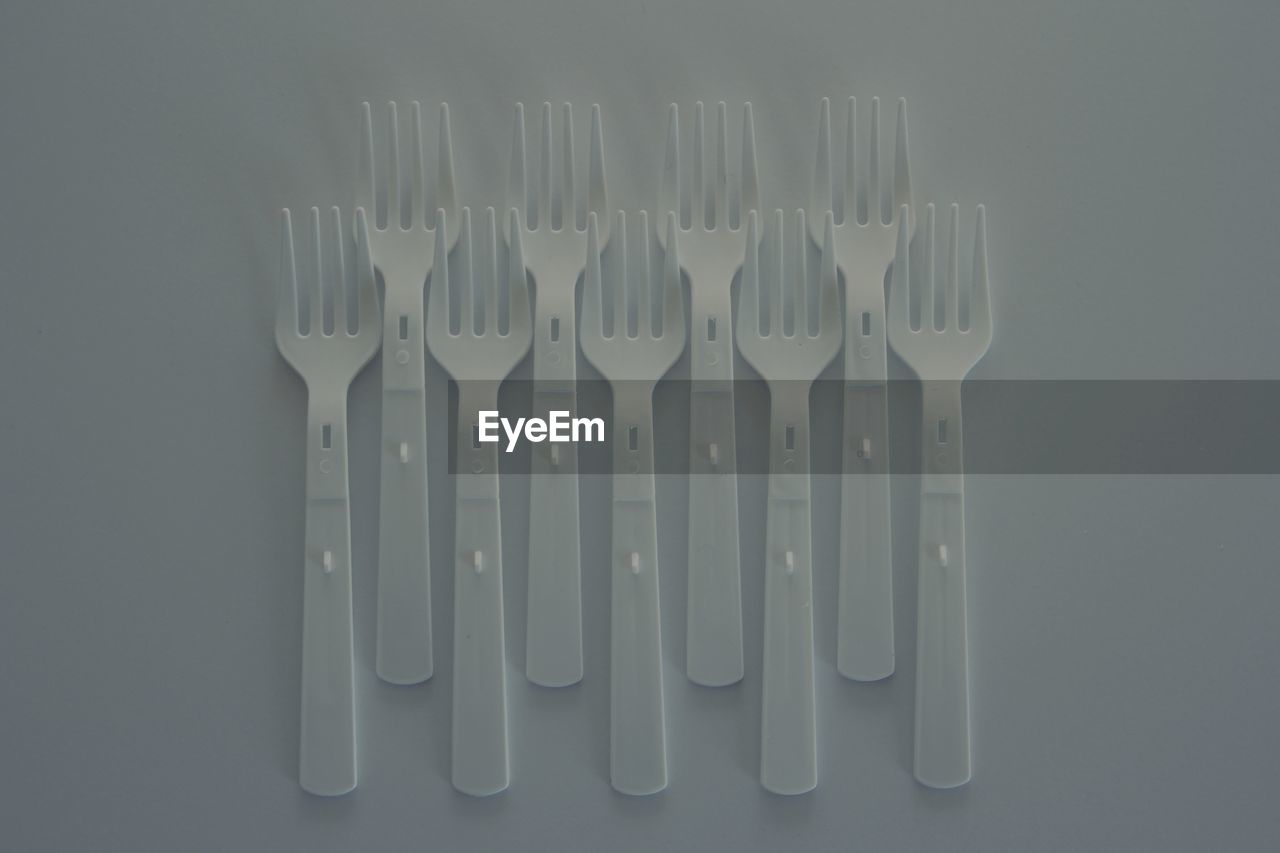 Directly above shot of forks arranged on white background