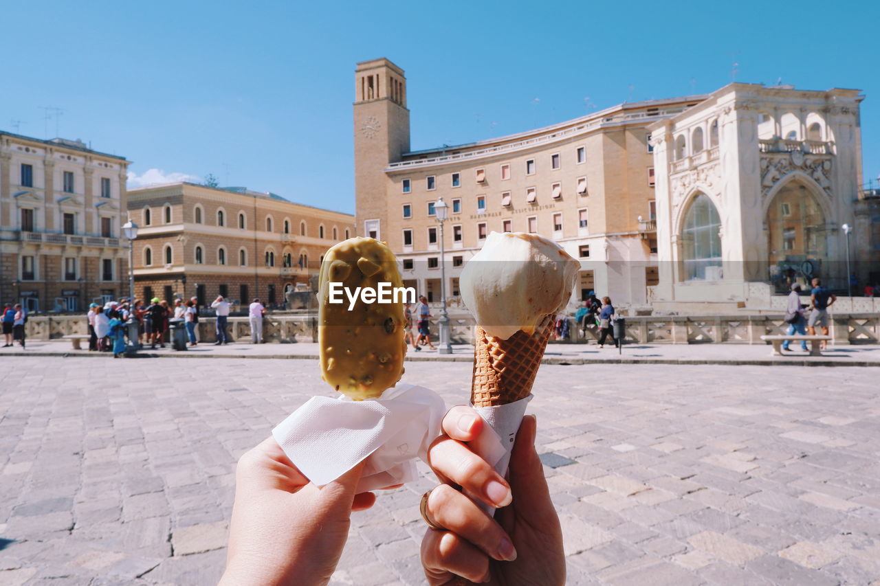 Cropped image of hand holding ice cream in city