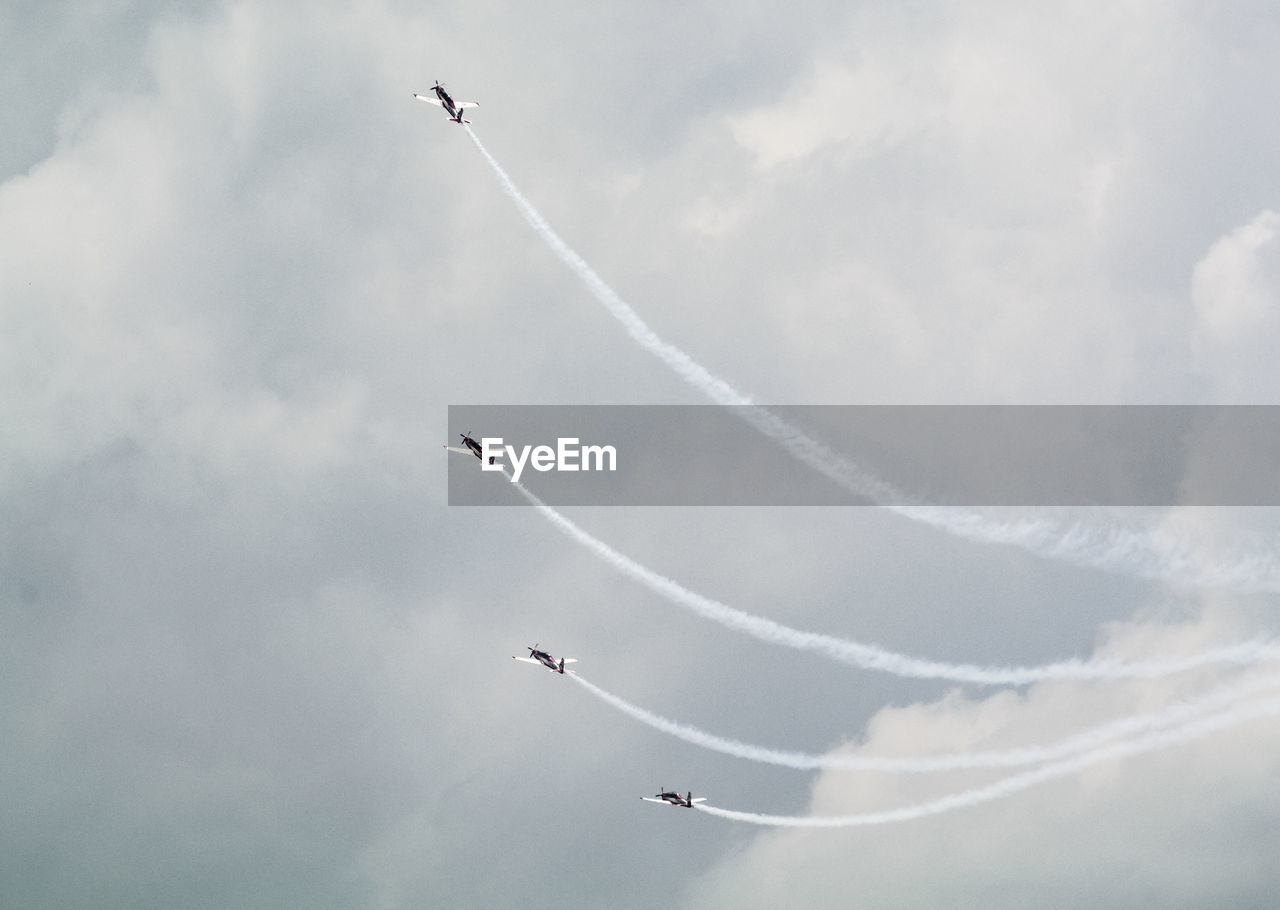 Low angle view of airplanes flying against blue sky