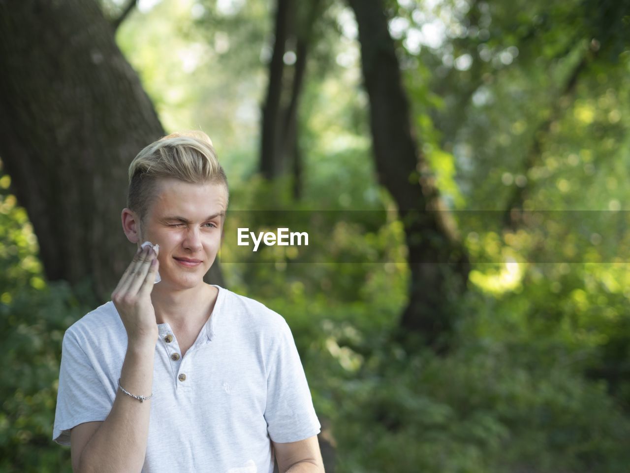 Young man cleaning face in forest