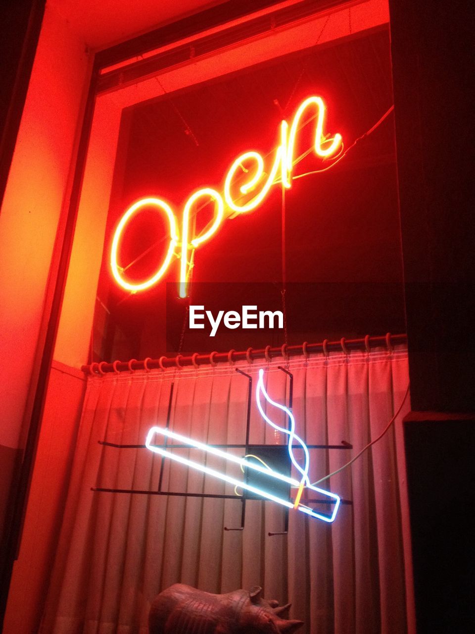 Low angle view of illuminated neon open sign on store window at night