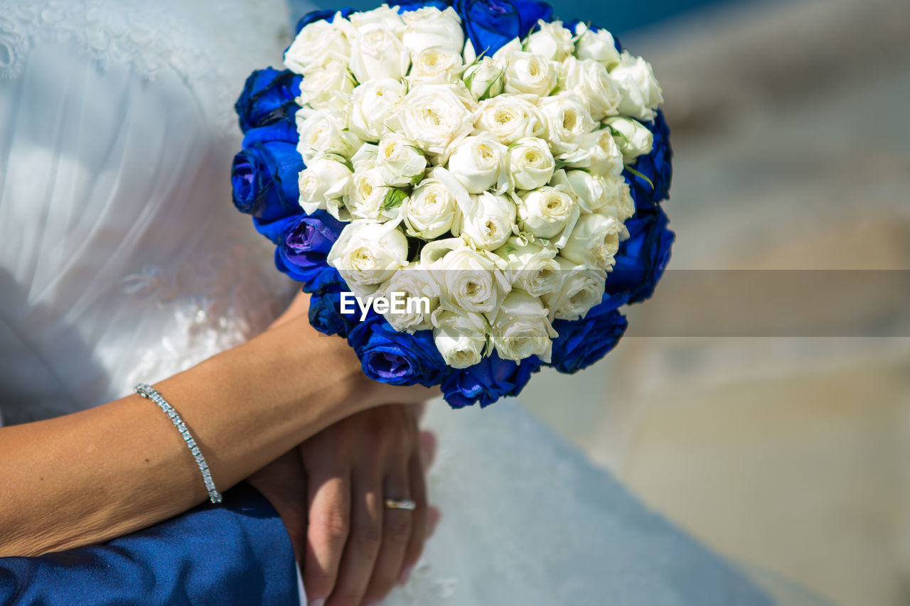 Midsection of bride holding rose bouquet